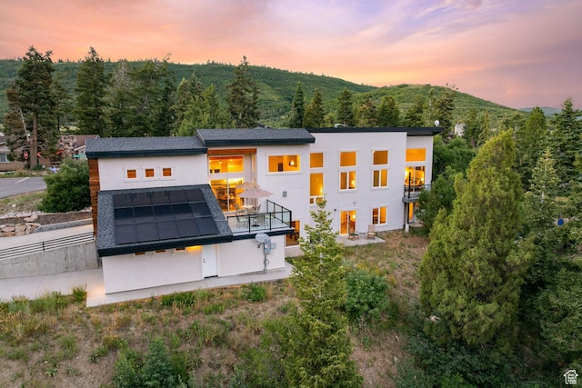 249 S Parkview Dr E, Park City, UT 84098 - back of house with solar panels, a balcony, stucco siding, and a wooded view