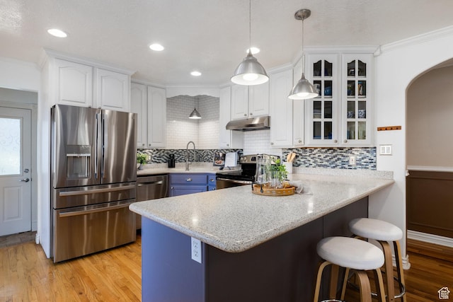 2400 E Logan Way S, Salt Lake City, UT 84108 - kitchen with stainless steel appliances, under cabinet range hood, a peninsula, a kitchen breakfast bar, and arched walkways