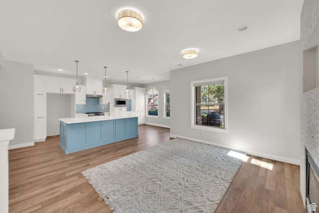 960 E 6740 S, Midvale, UT 84047 - kitchen with stainless steel microwave, tasteful backsplash, light countertops, white cabinetry, and light wood-type flooring