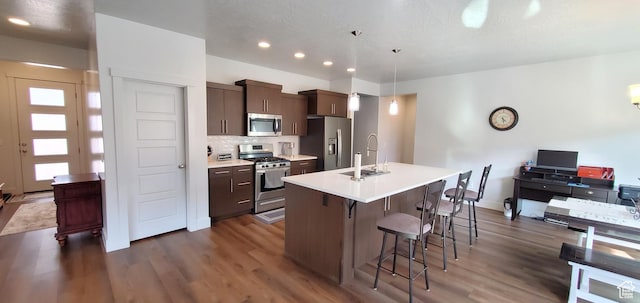 3040 E Lavatera Dr S, St George, UT 84790 - kitchen featuring stainless steel appliances, a breakfast bar, dark wood-style floors, a kitchen island with sink, and recessed lighting