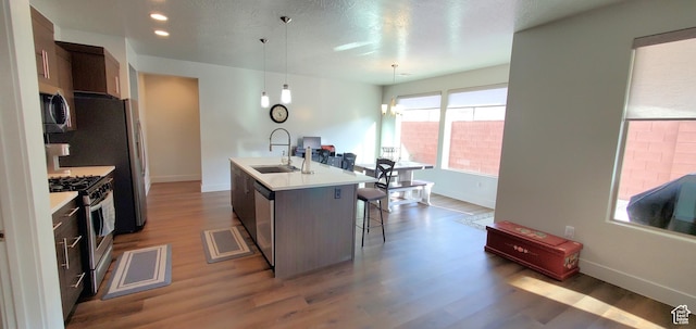 3040 E Lavatera Dr S, St George, UT 84790 - kitchen featuring stainless steel appliances, wood finished floors, a center island with sink, light countertops, and a kitchen breakfast bar