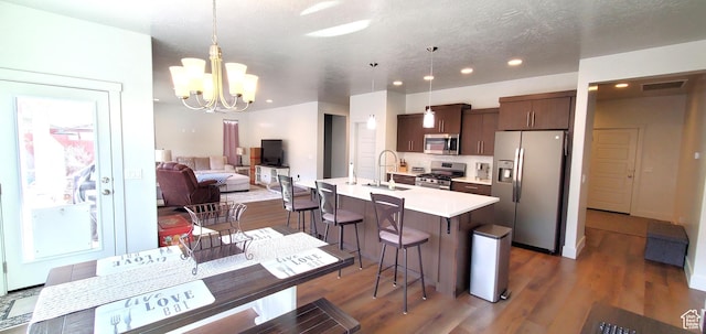 3040 E Lavatera Dr S, St George, UT 84790 - kitchen featuring stainless steel appliances, light countertops, a breakfast bar, dark brown cabinets, and a chandelier