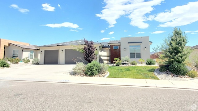 3040 E Lavatera Dr S, St George, UT 84790 - modern home featuring stucco siding, an attached garage, driveway, and solar panels