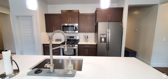 3040 E Lavatera Dr S, St George, UT 84790 - kitchen featuring appliances with stainless steel finishes, light countertops, dark brown cabinetry, and tasteful backsplash
