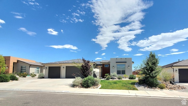3040 E Lavatera Dr S, St George, UT 84790 - view of front facade with a garage, stucco siding, driveway, and solar panels