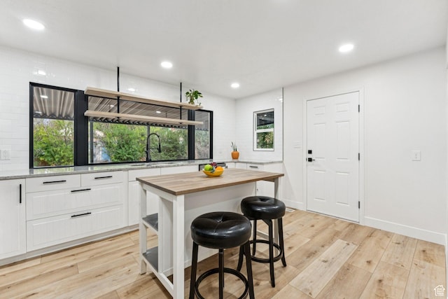 1043 S 1300 W, Salt Lake City, UT 84104 - kitchen featuring wood counters, white cabinetry, light wood-style floors, a kitchen bar, and recessed lighting