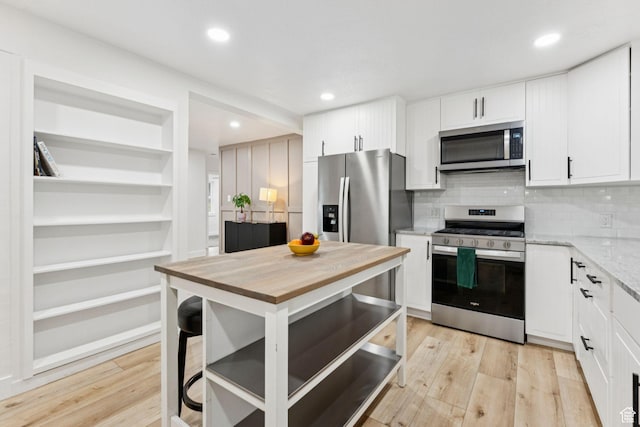 1043 S 1300 W, Salt Lake City, UT 84104 - kitchen featuring appliances with stainless steel finishes, white cabinetry, light stone countertops, light wood-type flooring, and recessed lighting