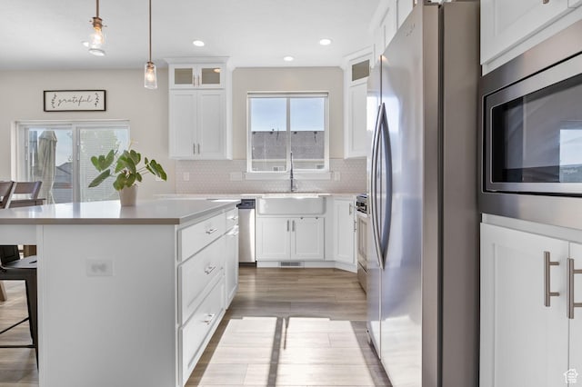 4982 N Goosefoot Dr Unit 51, Eagle Mountain, UT 84005 - kitchen with stainless steel appliances, a kitchen breakfast bar, a kitchen island, light wood-style floors, and glass insert cabinets