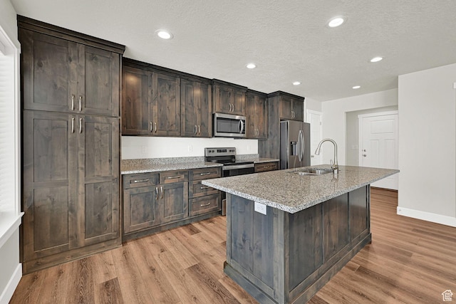 2782 W 4140 S Unit 246, Roy, UT 84067 - kitchen with stainless steel appliances, light wood finished floors, a kitchen island with sink, dark brown cabinetry, and recessed lighting