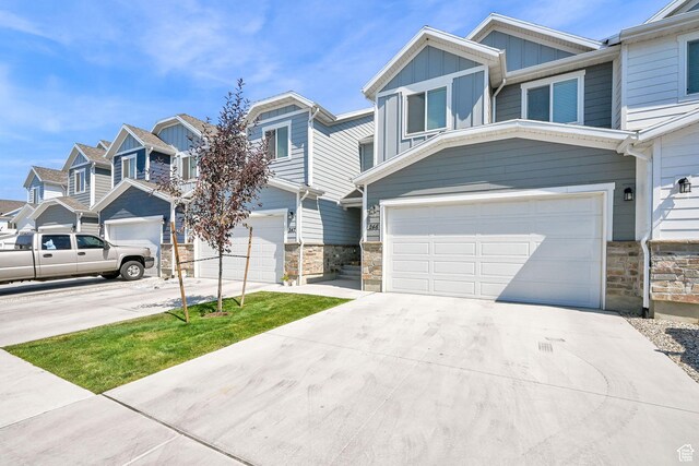 2782 W 4140 S Unit 246, Roy, UT 84067 - view of front of property featuring a garage, board and batten siding, concrete driveway, stone siding, and a residential view