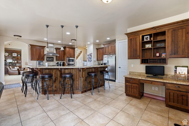 358 S 1040 W, Hurricane, UT 84737 - kitchen with wall chimney range hood, appliances with stainless steel finishes, built in desk, arched walkways, and recessed lighting