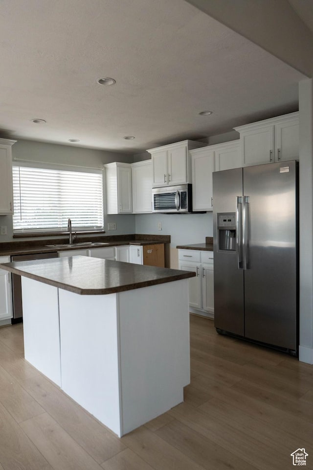4636 E Ponderosa Way, Eagle Mountain, UT 84005 - kitchen with appliances with stainless steel finishes, light wood-style floors, dark countertops, white cabinetry, and a center island