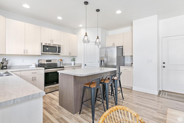4857 N Goosefoot Dr, Eagle Mountain, UT 84005 - kitchen with stainless steel appliances, light wood-style flooring, a breakfast bar area, light countertops, and recessed lighting