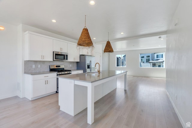 753 W Crystal Creek Rd, American Fork, UT 84003 - kitchen featuring appliances with stainless steel finishes, decorative backsplash, a kitchen island with sink, white cabinets, and light wood finished floors