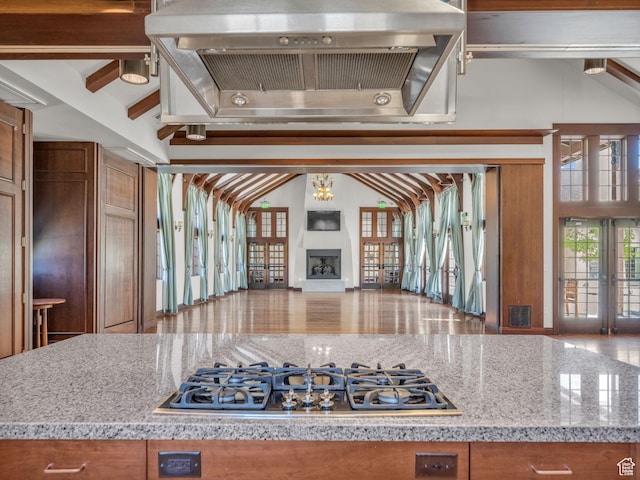 5103 W Black Twig Dr, South Jordan, UT 84009 - kitchen featuring stainless steel gas cooktop, extractor fan, open floor plan, brown cabinetry, and a fireplace with raised hearth
