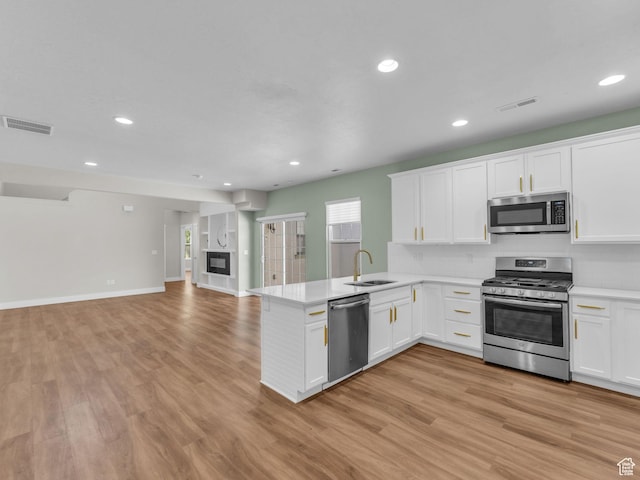 5103 W Black Twig Dr, South Jordan, UT 84009 - kitchen featuring appliances with stainless steel finishes, a peninsula, light countertops, white cabinetry, and light wood finished floors
