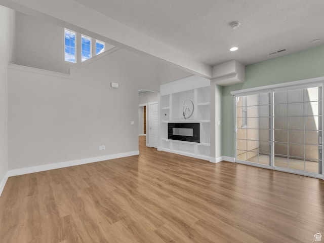 5103 W Black Twig Dr, South Jordan, UT 84009 - unfurnished living room with light wood finished floors, recessed lighting, healthy amount of natural light, built in features, and a textured ceiling