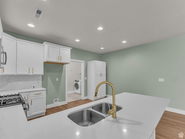 5103 W Black Twig Dr, South Jordan, UT 84009 - kitchen featuring washer / dryer, range with gas cooktop, white cabinetry, light wood-type flooring, and decorative backsplash