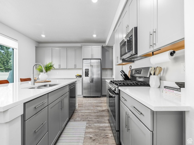 1911 N Lemongrass Dr, Saratoga Springs, UT 84045 - kitchen featuring stainless steel appliances, gray cabinetry, light wood-style flooring, recessed lighting, and light countertops