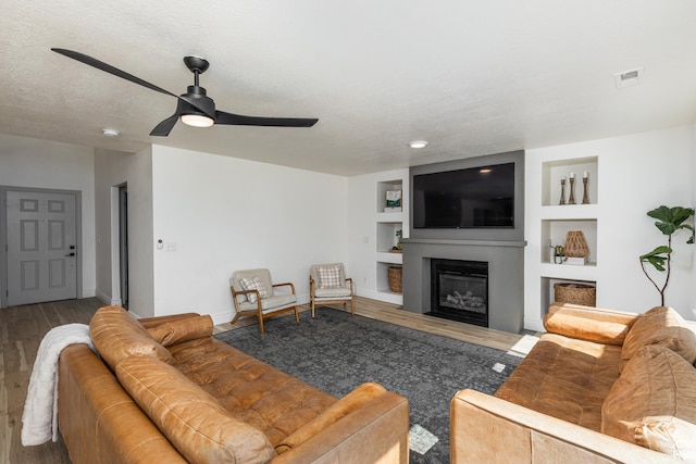 1012 N Cambria Dr, North Salt Lake, UT 84054 - living room featuring wood finished floors, a ceiling fan, built in features, and a glass covered fireplace