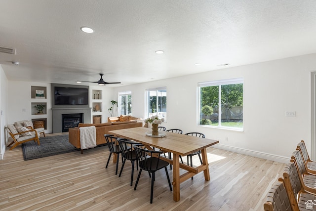 1012 N Cambria Dr, North Salt Lake, UT 84054 - dining space with light wood-type flooring, a glass covered fireplace, a textured ceiling, ceiling fan, and recessed lighting