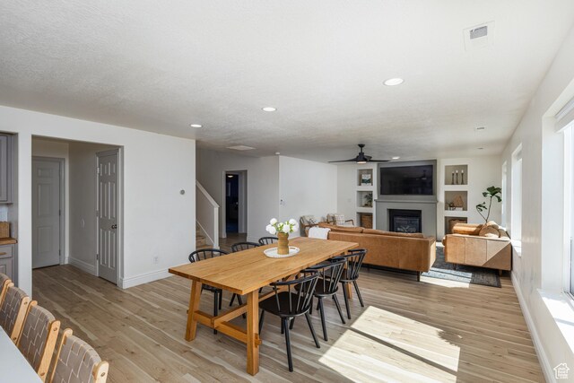 1012 N Cambria Dr, North Salt Lake, UT 84054 - dining space featuring stairway, ceiling fan, light wood finished floors, a glass covered fireplace, and recessed lighting