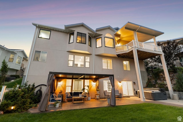 1044 S Terrace Dr E, Bountiful, UT 84010 - back of property at dusk featuring an outdoor living space, a hot tub, a balcony, stucco siding, and a patio