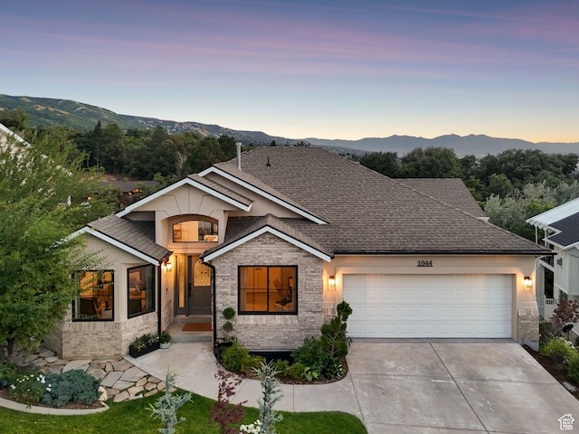 1044 S Terrace Dr E, Bountiful, UT 84010 - view of front of house featuring a garage, concrete driveway, a mountain view, stone siding, and roof with shingles