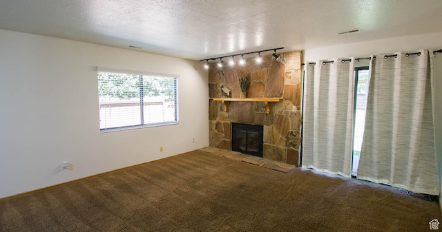 558 E 2025 N, North Ogden, UT 84414 - unfurnished living room featuring carpet floors, track lighting, a stone fireplace, and a textured ceiling