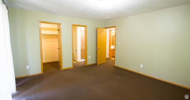 558 E 2025 N, North Ogden, UT 84414 - unfurnished bedroom with a walk in closet, a textured ceiling, and dark colored carpet
