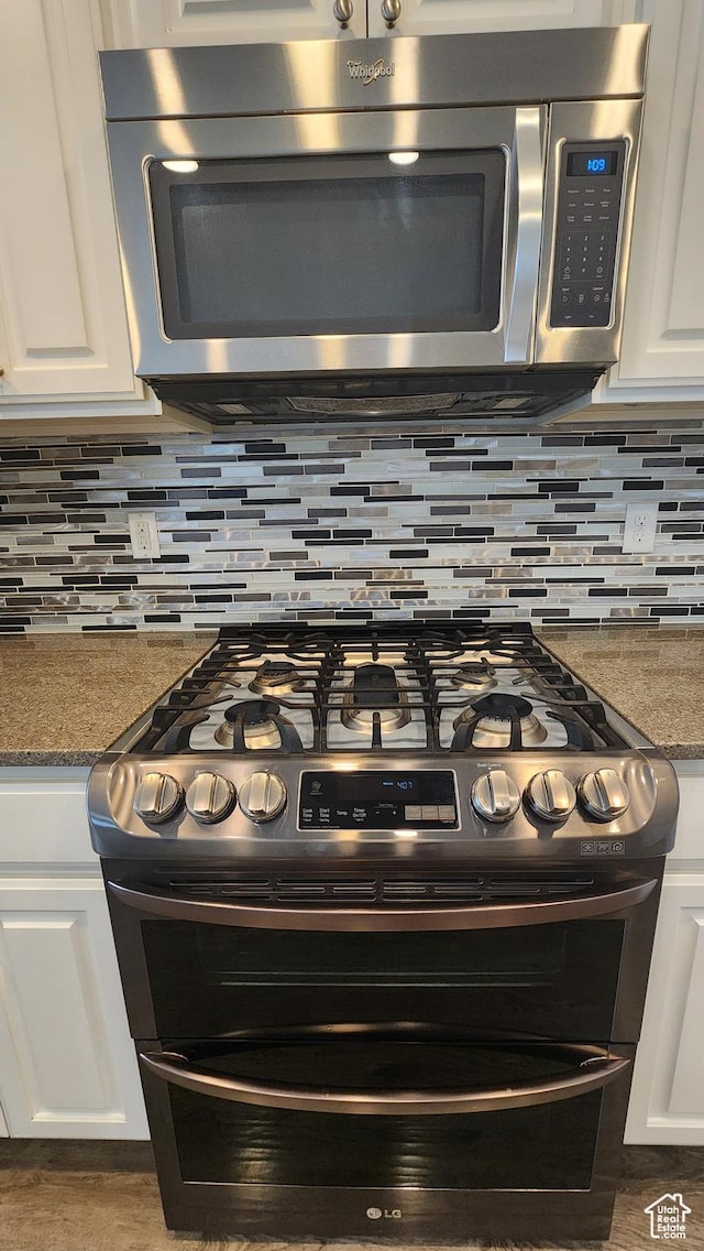 4442 W Hill Shadow Way S, Herriman, UT 84096 - kitchen view of stainless steel appliances, white cabinetry, decorative backsplash, and stone countertops