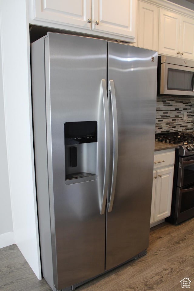 4442 W Hill Shadow Way S, Herriman, UT 84096 - kitchen featuring stainless steel appliances, wood finished floors, white cabinetry, decorative backsplash, and dark countertops