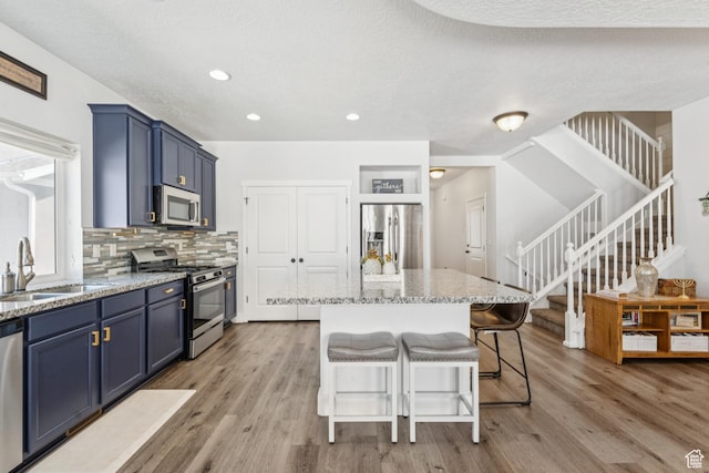 1076 S Meadow Walk Ln, Heber City, UT 84032 - kitchen featuring stainless steel appliances, blue cabinetry, light wood-style floors, light stone countertops, and recessed lighting