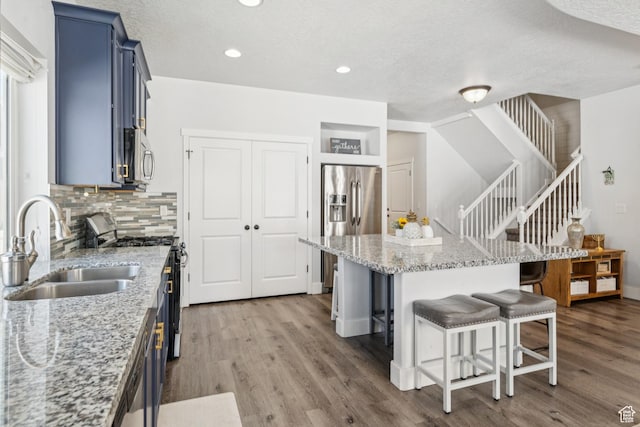 1076 S Meadow Walk Ln, Heber City, UT 84032 - kitchen with blue cabinets, stainless steel appliances, a kitchen breakfast bar, wood finished floors, and recessed lighting
