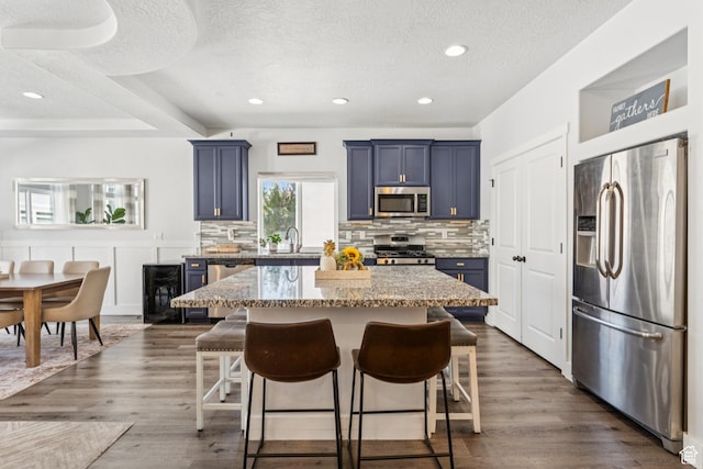 1076 S Meadow Walk Ln, Heber City, UT 84032 - kitchen with stainless steel appliances, blue cabinets, a kitchen bar, a kitchen island, and tasteful backsplash