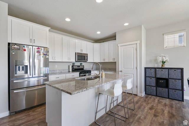 1017 W Coyote Gulch Way S Unit 117, Bluffdale, UT 84065 - kitchen featuring stainless steel appliances, white cabinets, dark wood-type flooring, a kitchen bar, and light stone counters