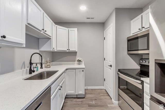 3699 S Botticelli Ct Unit C, Salt Lake City, UT 84119 - kitchen with appliances with stainless steel finishes, light wood-style flooring, white cabinetry, and light stone counters