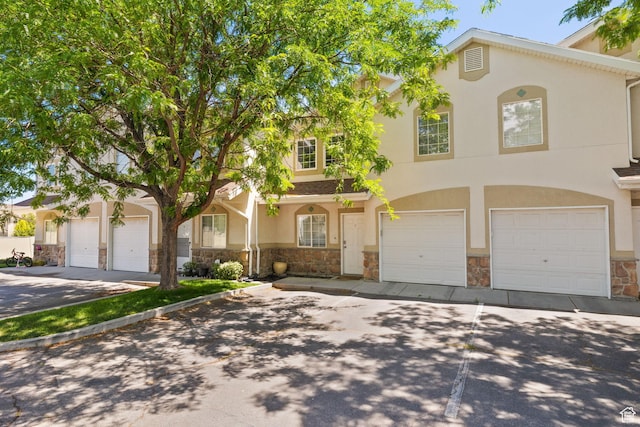 3699 S Botticelli Ct Unit C, Salt Lake City, UT 84119 - view of front of house with stone siding, an attached garage, concrete driveway, and stucco siding