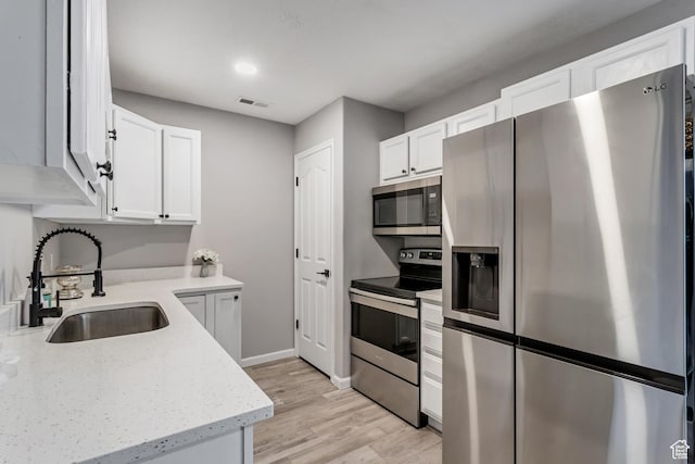 3699 S Botticelli Ct Unit C, Salt Lake City, UT 84119 - kitchen with stainless steel appliances, white cabinets, light wood-style floors, and light stone countertops