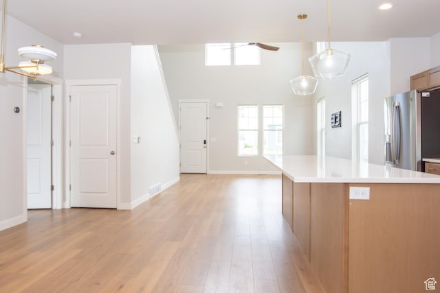 11511 S Pebble Pond Rd, South Jordan, UT 84009 - kitchen with stainless steel fridge, light countertops, light wood-style flooring, hanging light fixtures, and a ceiling fan