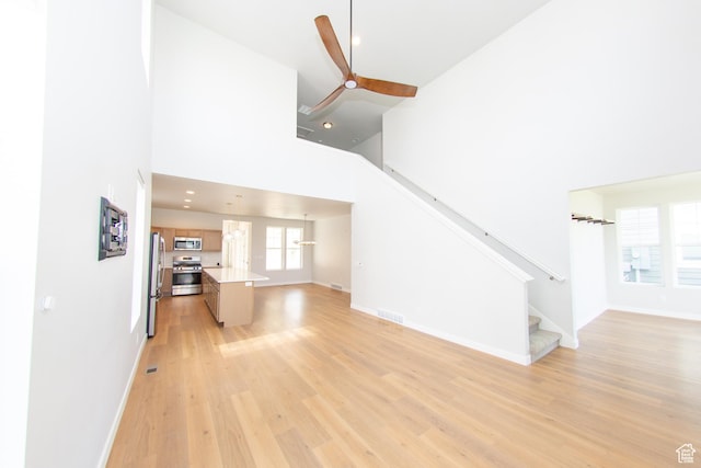 11511 S Pebble Pond Rd, South Jordan, UT 84009 - unfurnished living room featuring a towering ceiling, ceiling fan, light wood-type flooring, stairs, and recessed lighting