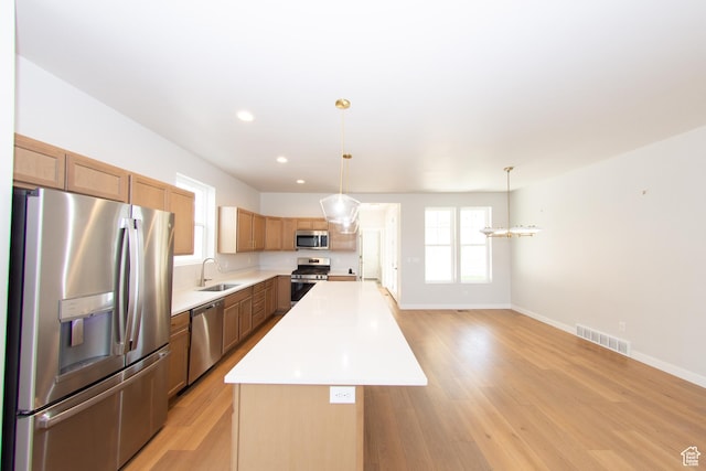 11511 S Pebble Pond Rd, South Jordan, UT 84009 - kitchen with stainless steel appliances, a center island, light wood-style floors, light countertops, and decorative light fixtures