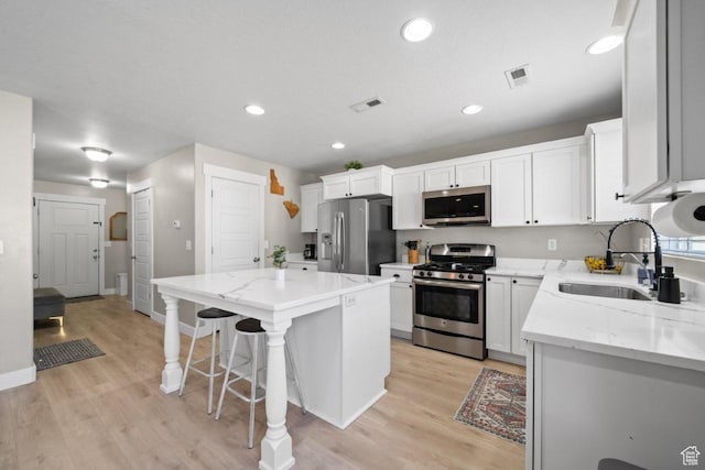 3634 S Creek Side Ln, Syracuse, UT 84075 - kitchen with stainless steel appliances, a center island, light wood-style flooring, a kitchen bar, and recessed lighting