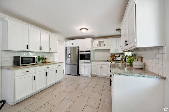 5726 S Highland Dr E, Holladay, UT 84121 - kitchen featuring appliances with stainless steel finishes, tasteful backsplash, and white cabinetry