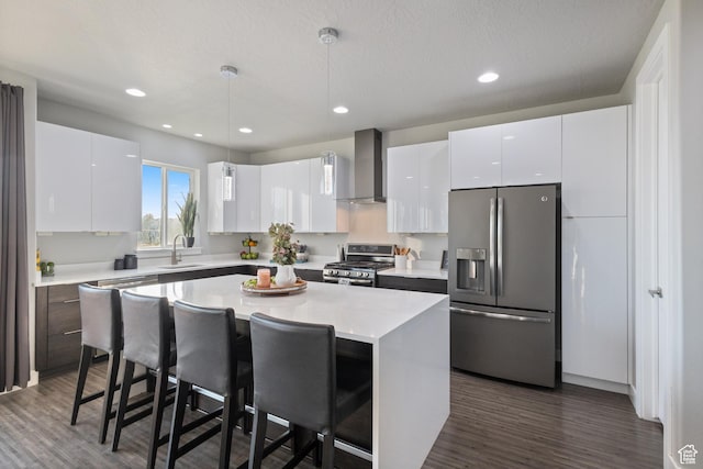 7672 N Evans Ranch Dr E, Eagle Mountain, UT 84005 - kitchen featuring appliances with stainless steel finishes, wall chimney exhaust hood, a breakfast bar, dark wood finished floors, and recessed lighting