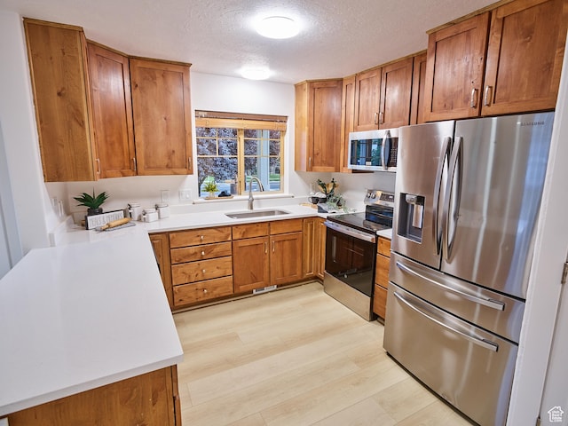 257 N 900 W, Provo, UT 84601 - kitchen featuring stainless steel appliances, brown cabinetry, light wood-style flooring, a textured ceiling, and light countertops