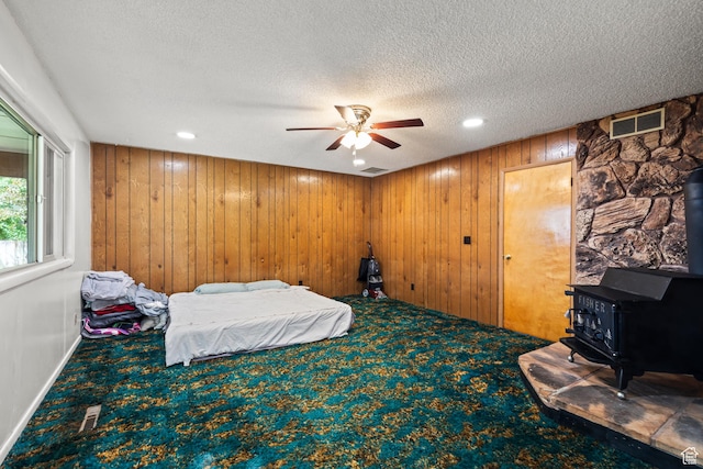 407 E 200 N, Richfield, UT 84701 - bedroom with a wood stove, carpet, a textured ceiling, wooden walls, and recessed lighting