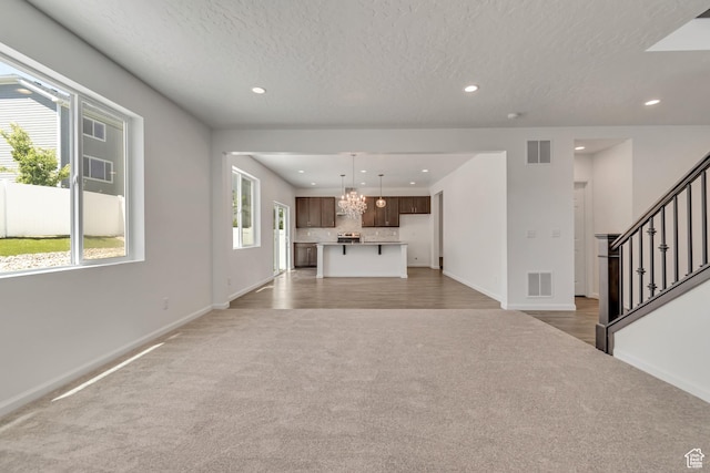 2123 N Wallflower Dr, Saratoga Springs, UT 84045 - unfurnished living room with light carpet, recessed lighting, stairs, a textured ceiling, and a chandelier