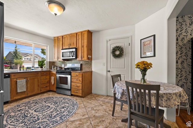 1770 E Vine St S, Salt Lake City, UT 84121 - kitchen with stainless steel appliances, brown cabinets, backsplash, a textured ceiling, and dark countertops