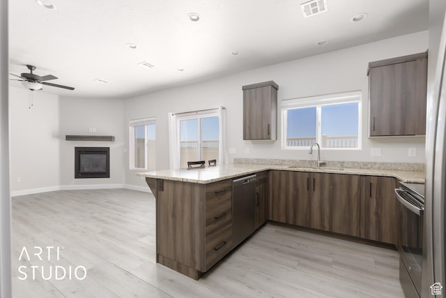 668 E Fiddlers Cove Dr Unit 35, Cedar City, UT 84721 - kitchen featuring stainless steel dishwasher, range, a peninsula, a glass covered fireplace, and light wood-type flooring